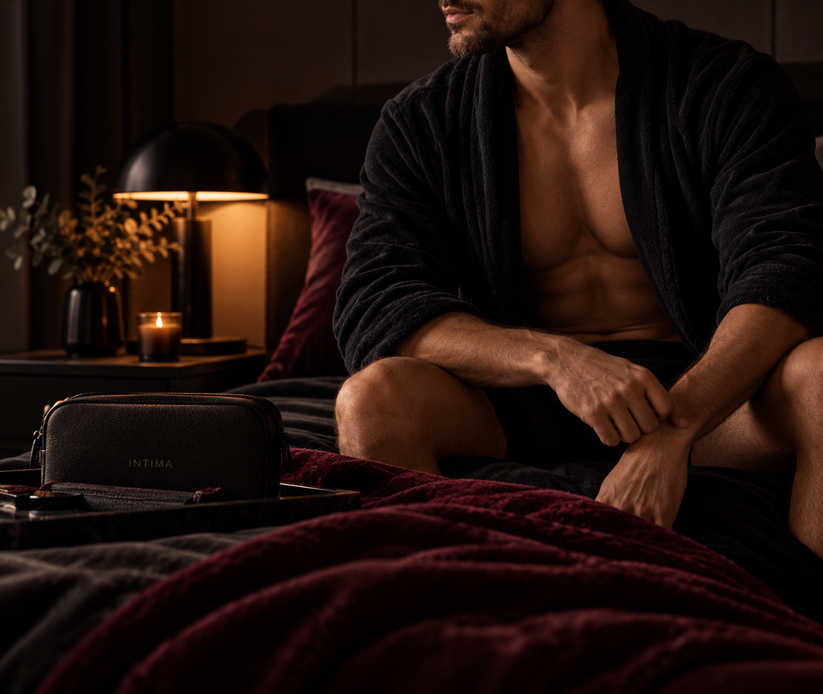 A man in a dark robe sitting on a bed.
