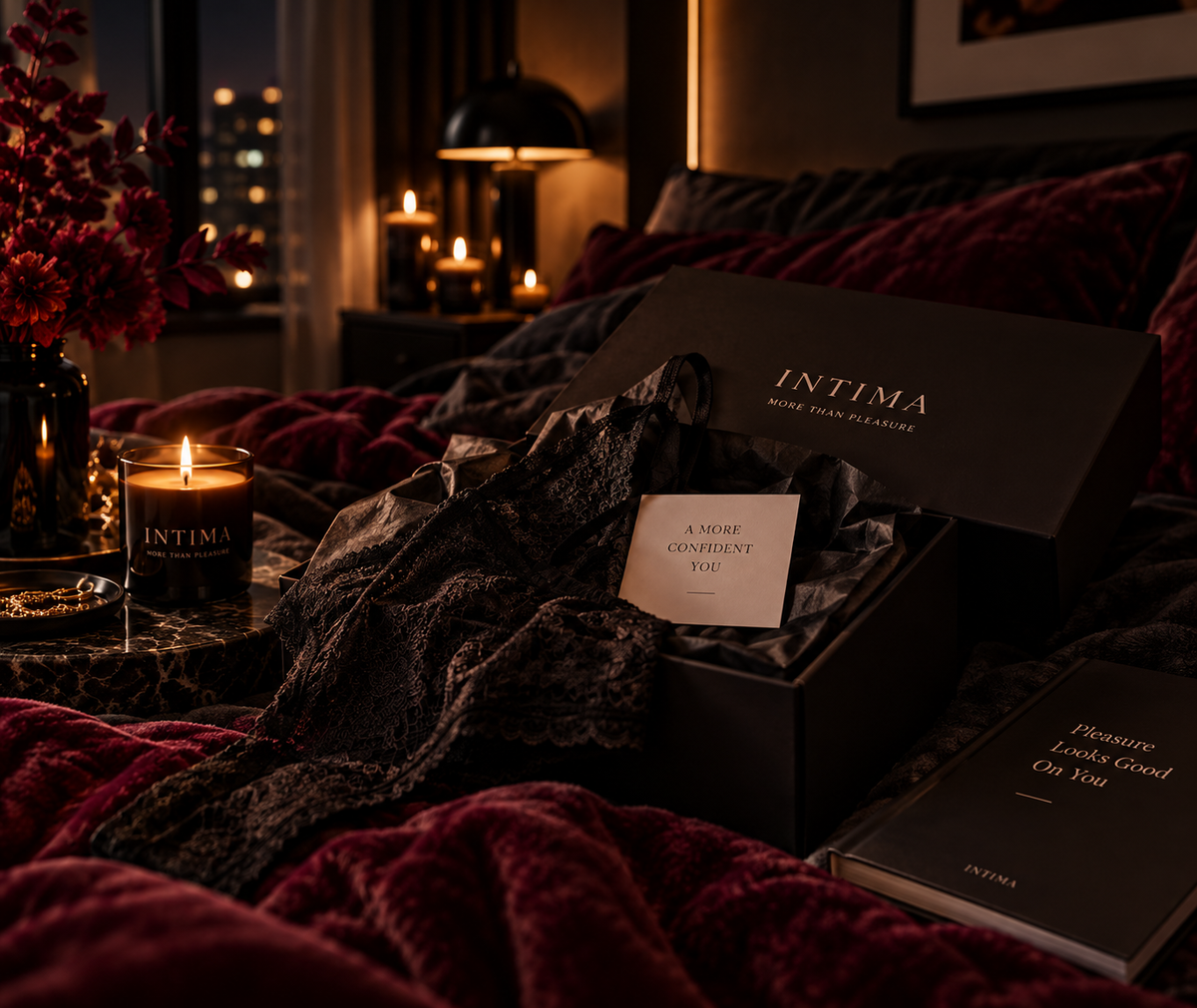 An INTIMA box and card on a bed beside a candle.