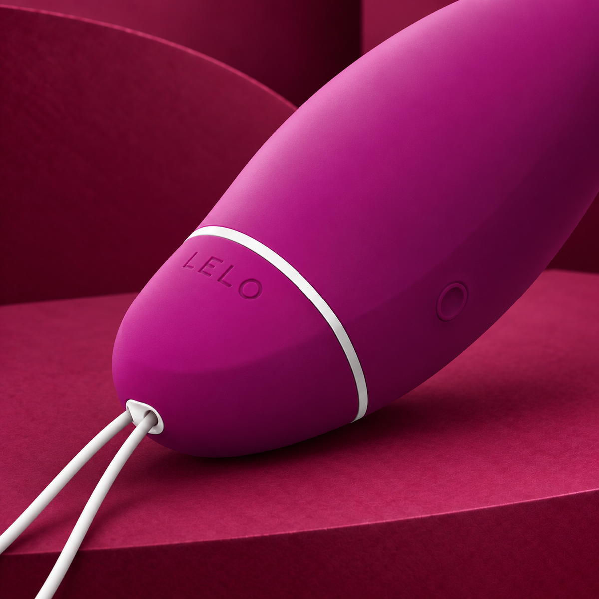LELO Luna Smart Bead purple ring, logo, control and white cord close detail on red geometric background