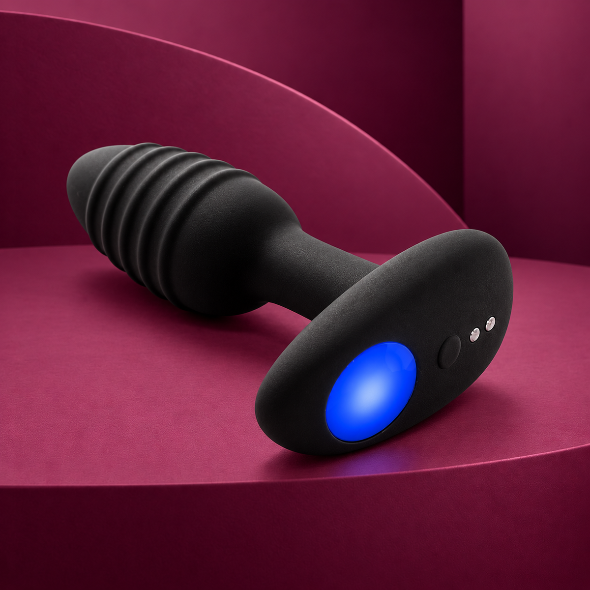 Kiiroo Lumen black ribbed plug with oval blue LED, control and two charging contacts on red geometric background