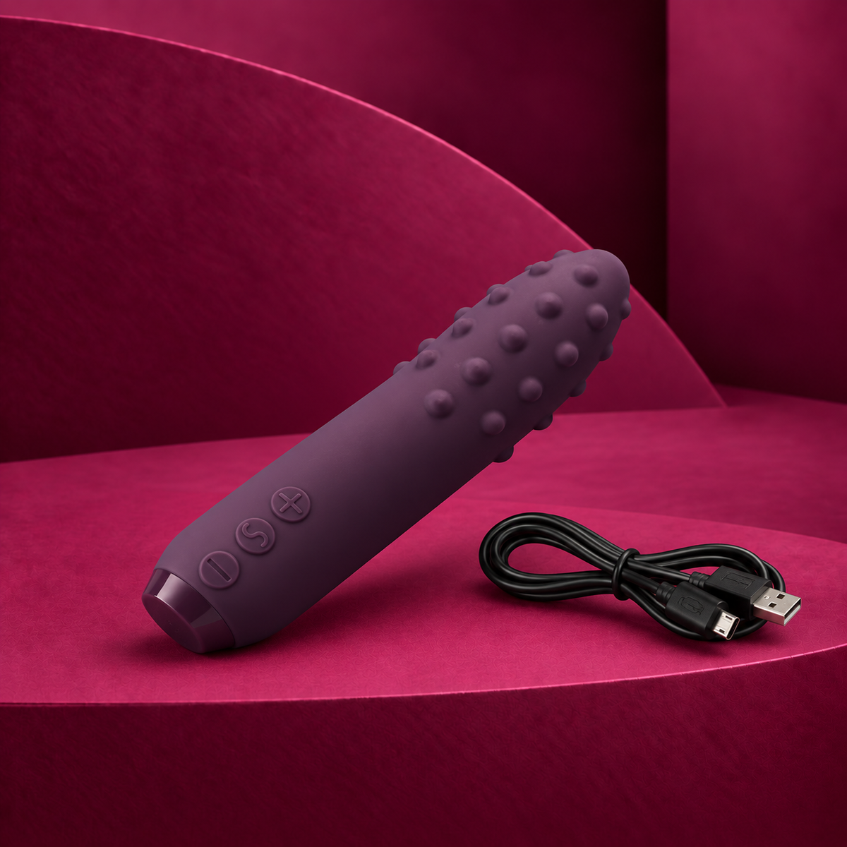 Je Joue Duet deep purple textured bullet with three controls and charging cable on red geometric background