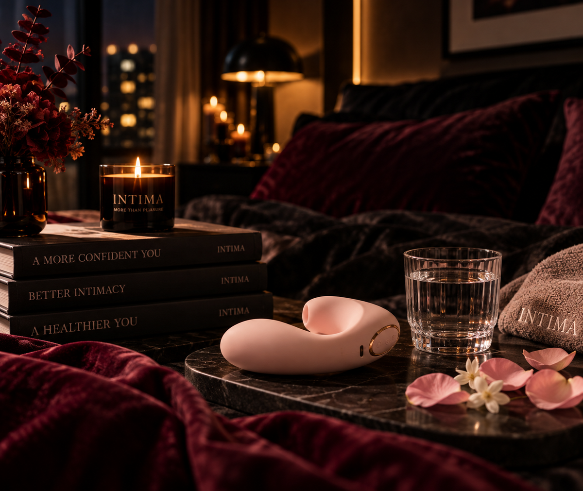 A pink intimate toy on a round table beside a glass and rose petals.