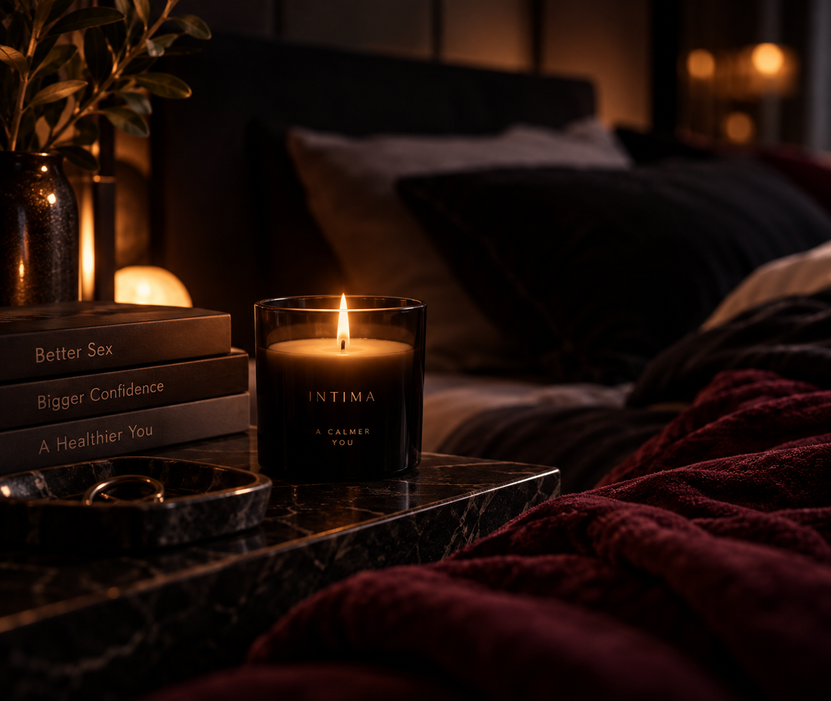 A lit candle beside books on a bedside table.